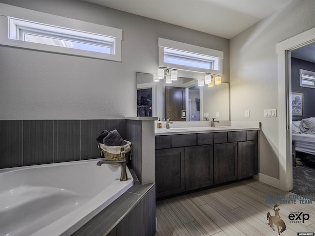 full bath featuring double vanity, a sink, baseboards, and ensuite bathroom