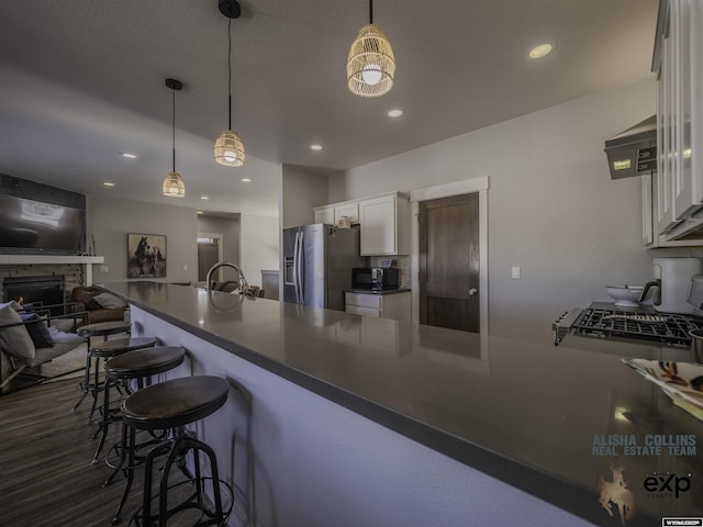 kitchen with dark countertops, stainless steel fridge, white cabinets, and a kitchen breakfast bar