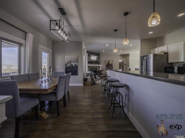 dining area featuring a fireplace, baseboards, dark wood-style flooring, and recessed lighting