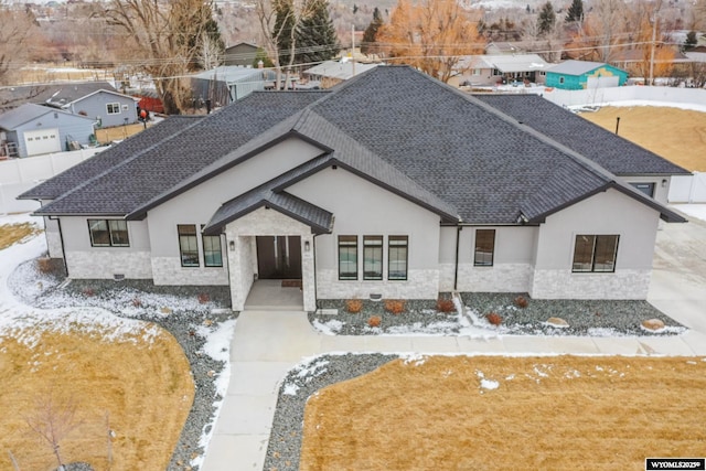 view of front facade with stone siding, stucco siding, and roof with shingles