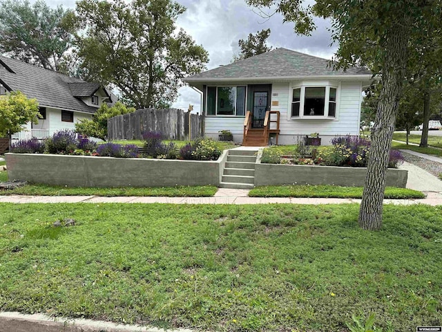 bungalow-style house with fence and a front lawn