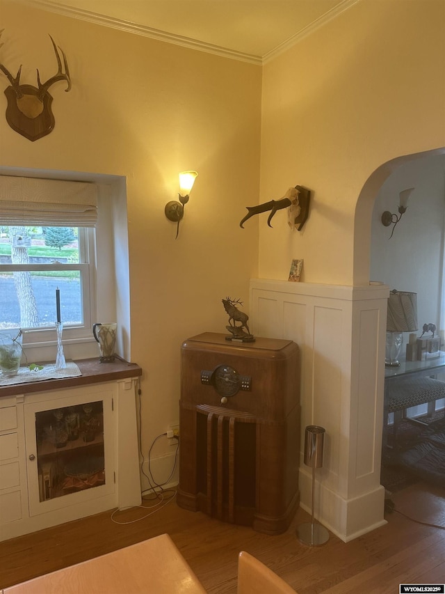 interior space featuring arched walkways, wood finished floors, and crown molding