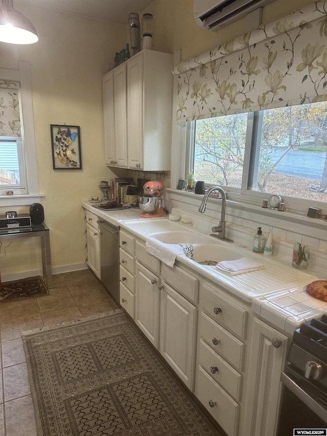 kitchen featuring dark tile patterned floors, a sink, white cabinets, tile counters, and dishwasher