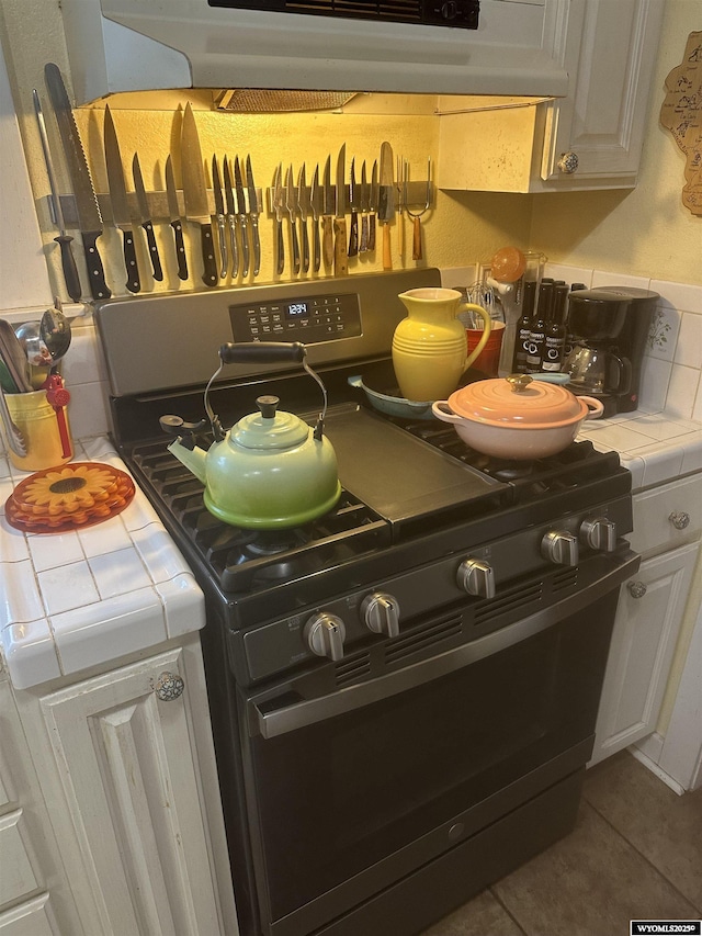 details featuring white cabinetry, tile countertops, and stove