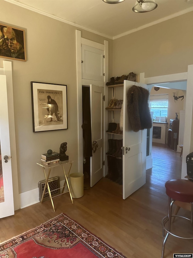 hall featuring a sink, crown molding, baseboards, and wood finished floors