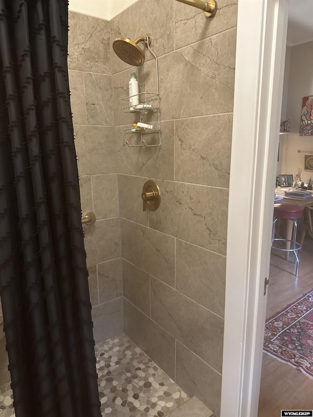 full bathroom with ornamental molding, tiled shower, and wood finished floors