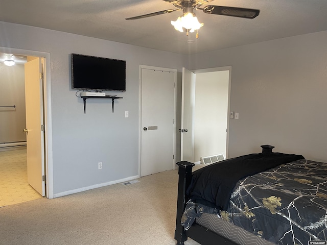 bedroom with a baseboard radiator, connected bathroom, visible vents, and a ceiling fan