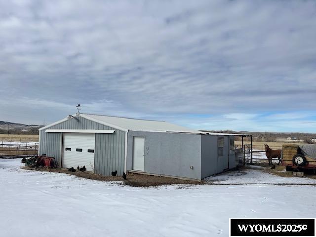 snow covered structure with fence and an outbuilding