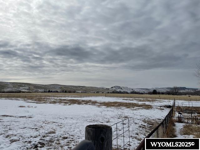 yard covered in snow featuring fence, a mountain view, and a rural view