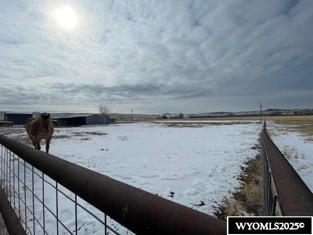 yard covered in snow with a rural view and fence