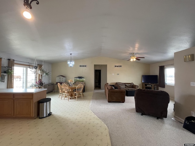 living area featuring light carpet, a healthy amount of sunlight, visible vents, and vaulted ceiling