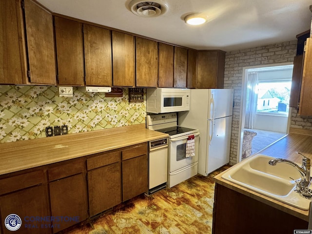 kitchen featuring light countertops, white appliances, a sink, and visible vents