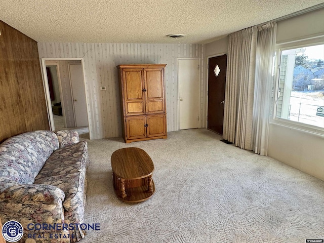 living room featuring light carpet, visible vents, and a textured ceiling