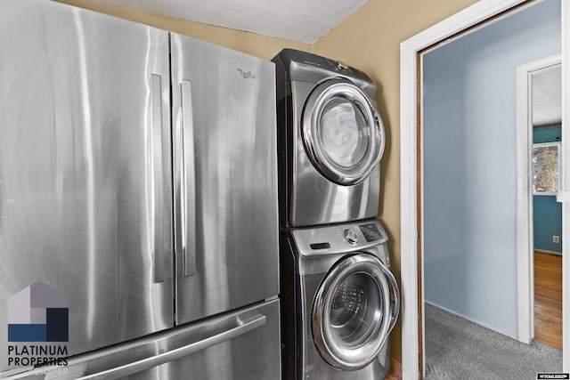 clothes washing area featuring carpet floors, laundry area, and stacked washing maching and dryer