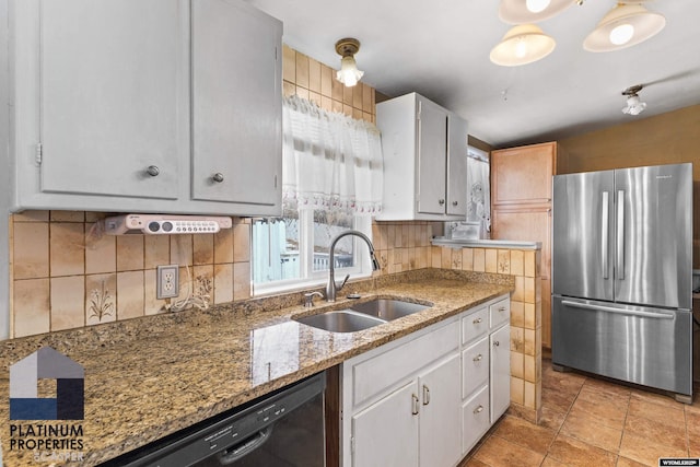 kitchen with stone countertops, white cabinetry, a sink, and freestanding refrigerator