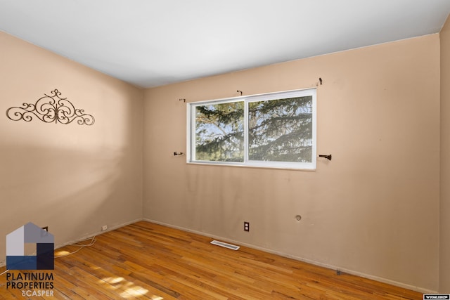 empty room with light wood finished floors and visible vents