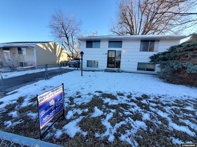 snow covered house featuring fence