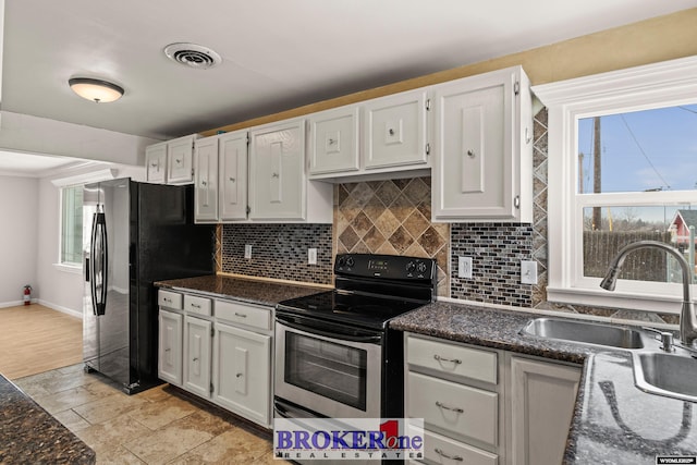 kitchen with electric range, visible vents, white cabinets, and black refrigerator with ice dispenser