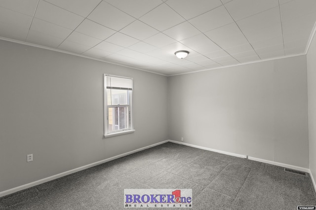 empty room featuring carpet floors, visible vents, crown molding, and baseboards