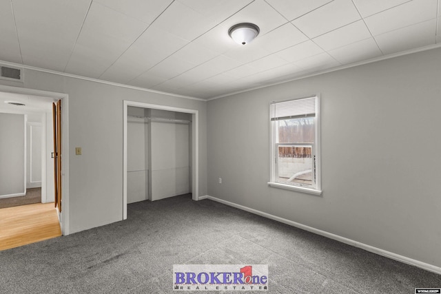 unfurnished bedroom featuring carpet floors, visible vents, a closet, and ornamental molding