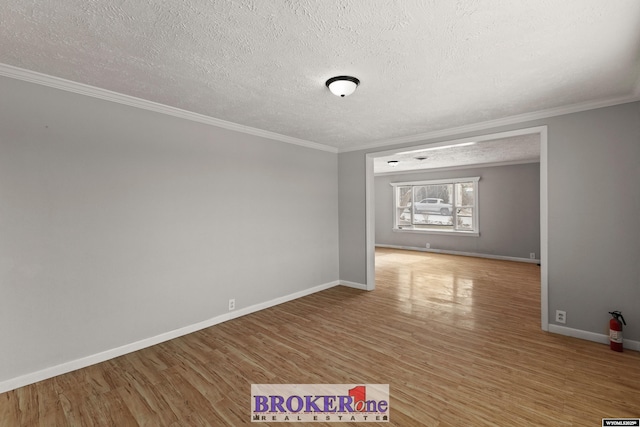 empty room featuring crown molding, light wood finished floors, a textured ceiling, and baseboards