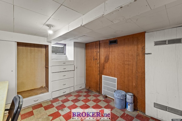 finished basement with dark floors, visible vents, and wooden walls