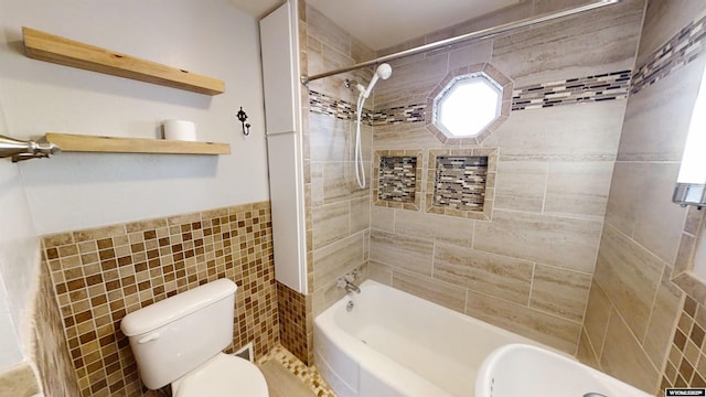 bathroom with toilet, shower / bath combination, tile walls, and wainscoting