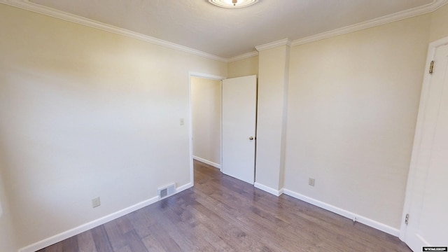 unfurnished room featuring ornamental molding, wood finished floors, visible vents, and baseboards