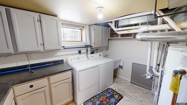 clothes washing area with gas water heater, washing machine and clothes dryer, cabinet space, a sink, and baseboards