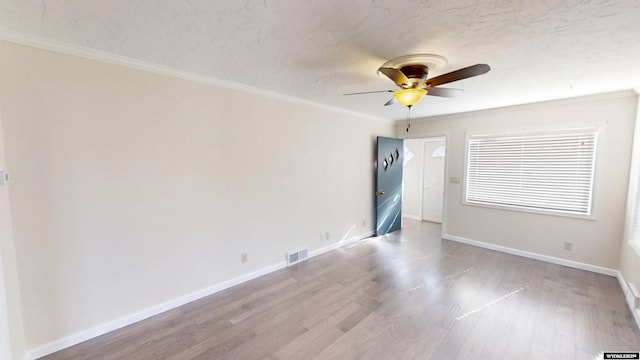 spare room with light wood-style floors, ornamental molding, a ceiling fan, a textured ceiling, and baseboards