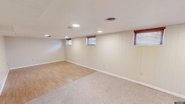 below grade area with baseboards, visible vents, and wood finished floors