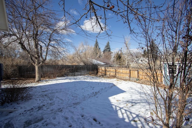 snowy yard featuring a fenced backyard