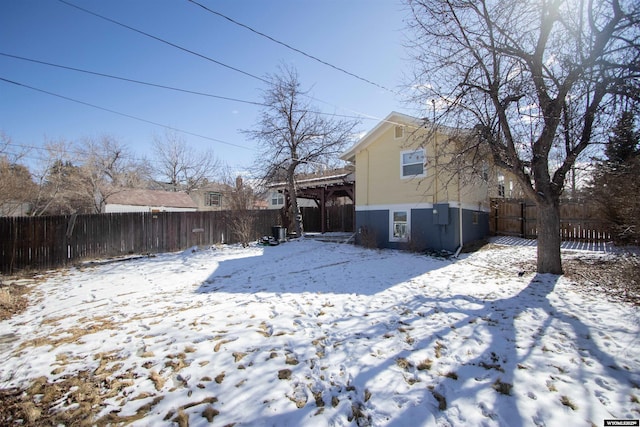 snow covered house featuring a fenced backyard and a pergola