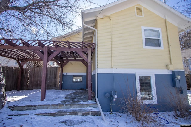 snow covered property featuring fence and a pergola