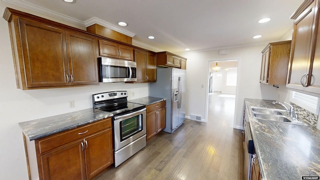 kitchen with visible vents, brown cabinetry, dark wood-style floors, appliances with stainless steel finishes, and a sink