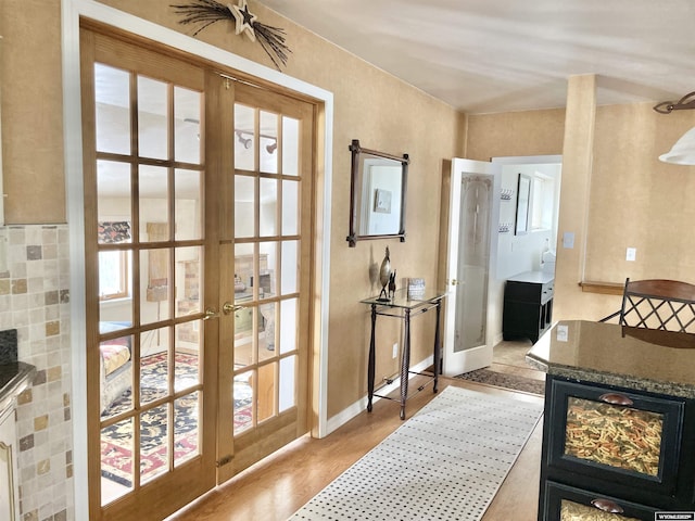 doorway with french doors, light wood-type flooring, and baseboards