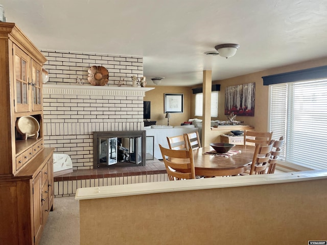 dining space with a fireplace, visible vents, and light colored carpet