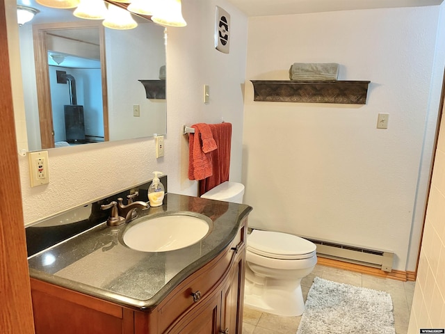 bathroom with toilet, baseboard heating, vanity, and tile patterned floors