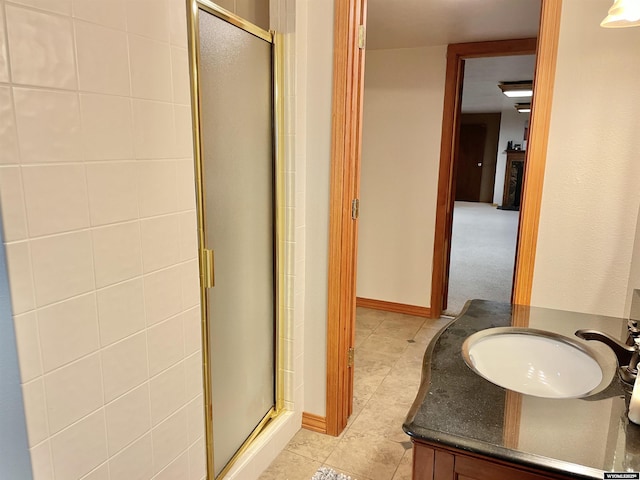 bathroom featuring tile patterned flooring, a shower stall, baseboards, and vanity