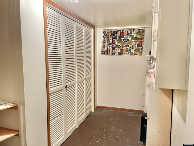 corridor with concrete flooring and baseboards