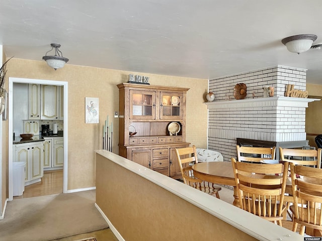 interior space with baseboards, a fireplace, glass insert cabinets, and light colored carpet