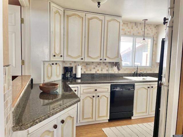 kitchen with black dishwasher, cream cabinetry, pendant lighting, and a sink