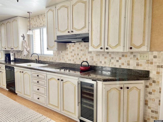 kitchen featuring dark countertops, under cabinet range hood, beverage cooler, and black dishwasher