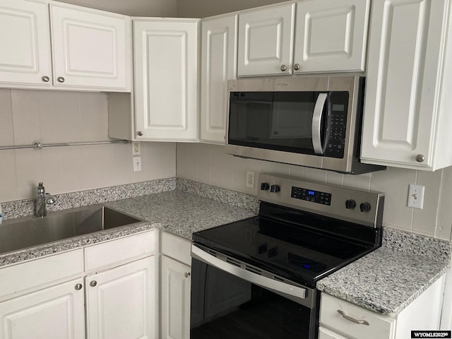 kitchen featuring stainless steel appliances, tasteful backsplash, a sink, and white cabinetry