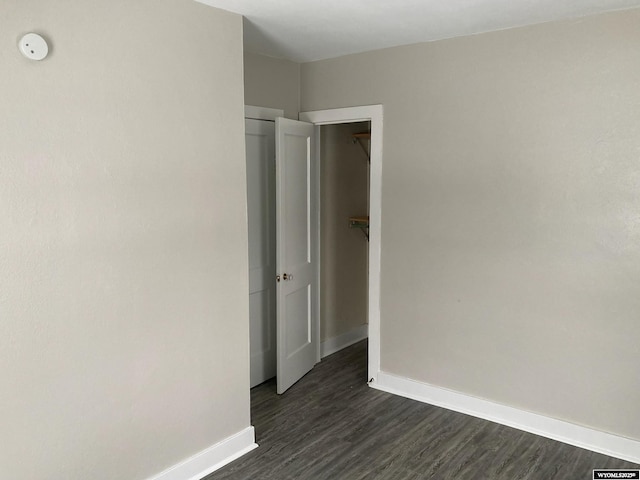 spare room featuring baseboards and dark wood-style flooring