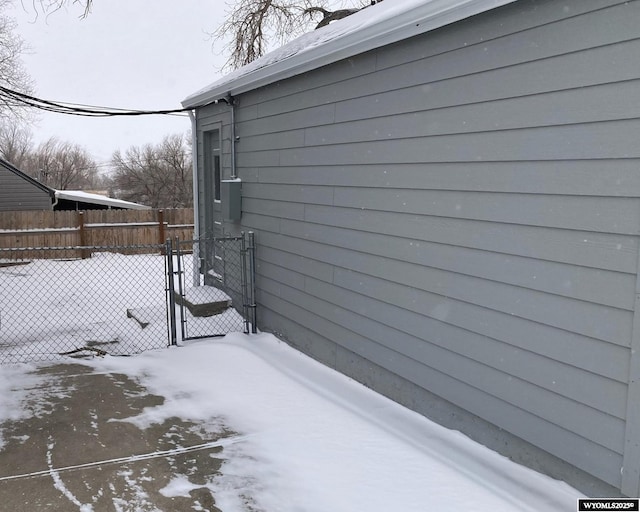 view of snowy exterior with a gate and fence