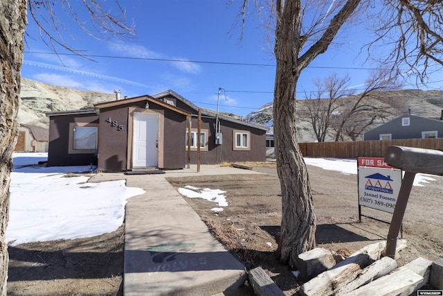 view of front of home with fence, a mountain view, and stucco siding