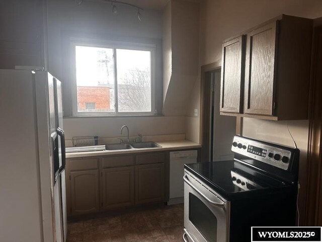 kitchen featuring electric range, white refrigerator with ice dispenser, dishwashing machine, light countertops, and a sink