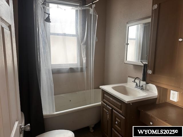 full bathroom featuring toilet, plenty of natural light, shower / bathtub combination with curtain, and vanity