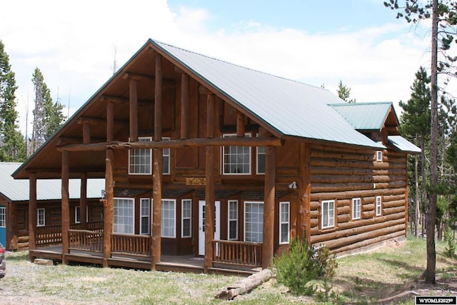 back of house featuring covered porch, metal roof, and log exterior